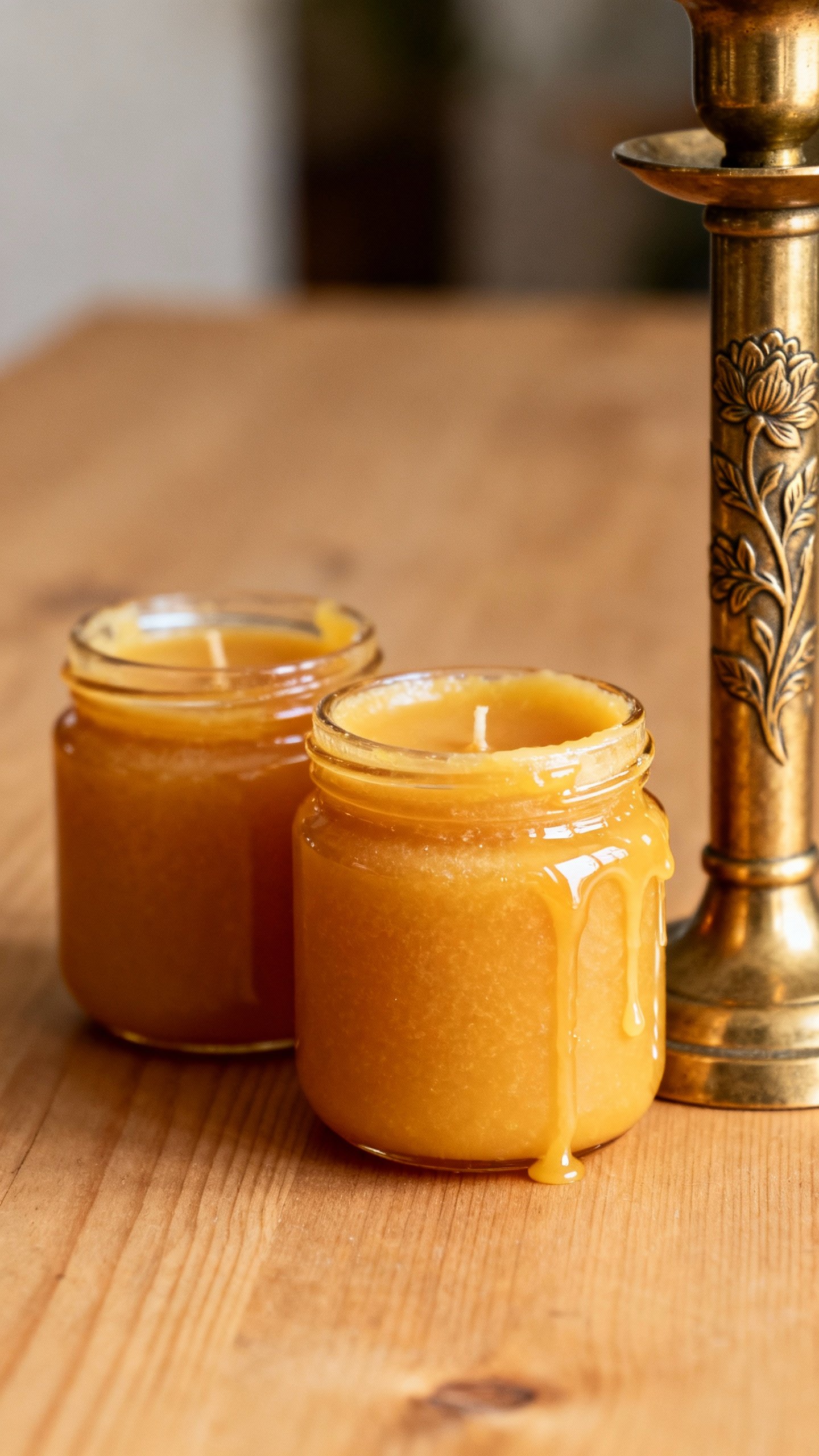 Beeswax candle jars cooling beside brass candlesticks