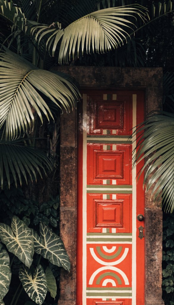 Bold door color vignette: terracotta + cream + olive, leafy backdrop